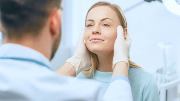 a female patient preparing for a facial procedure with her surgeon.
