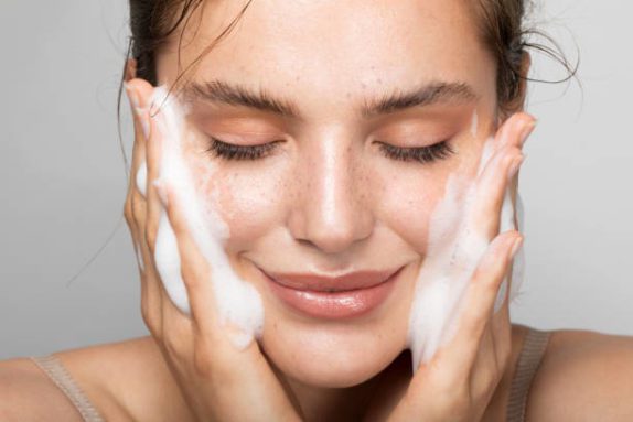 a woman applying skincare products to her face.